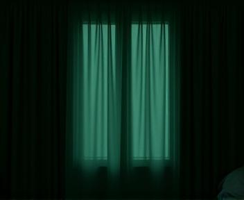 A neatly drawn blackout curtain in a bedroom, completely blocking out daylight, creating a dark, serene environment.